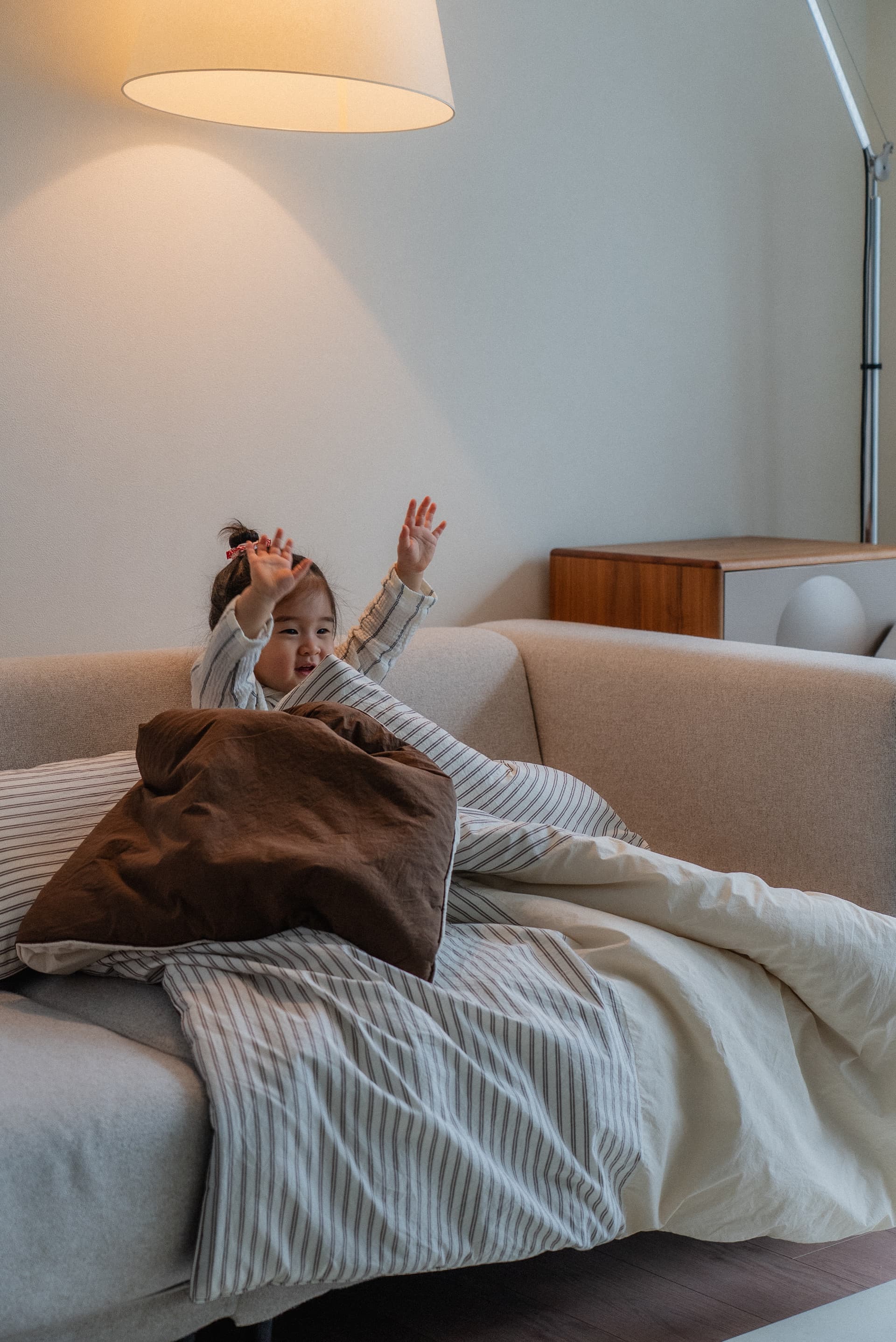 Toddler sitting on a sofa wrapped in striped bedding