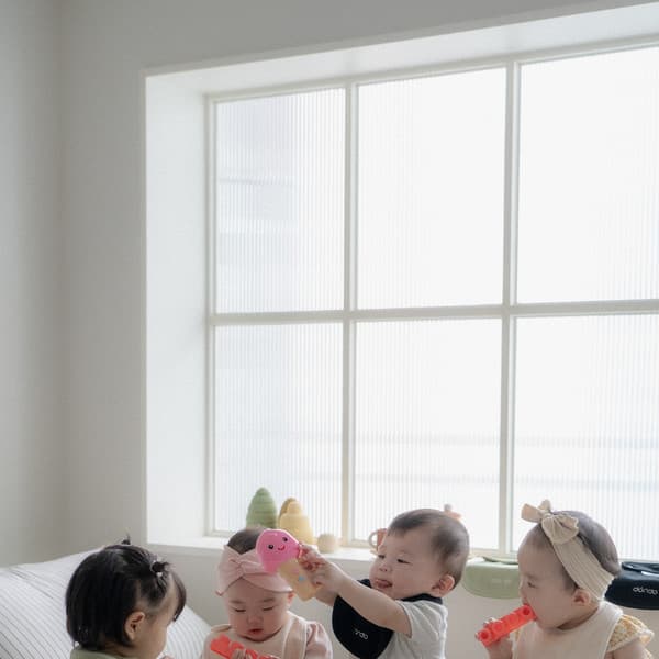 Four babies playing together on a white bed